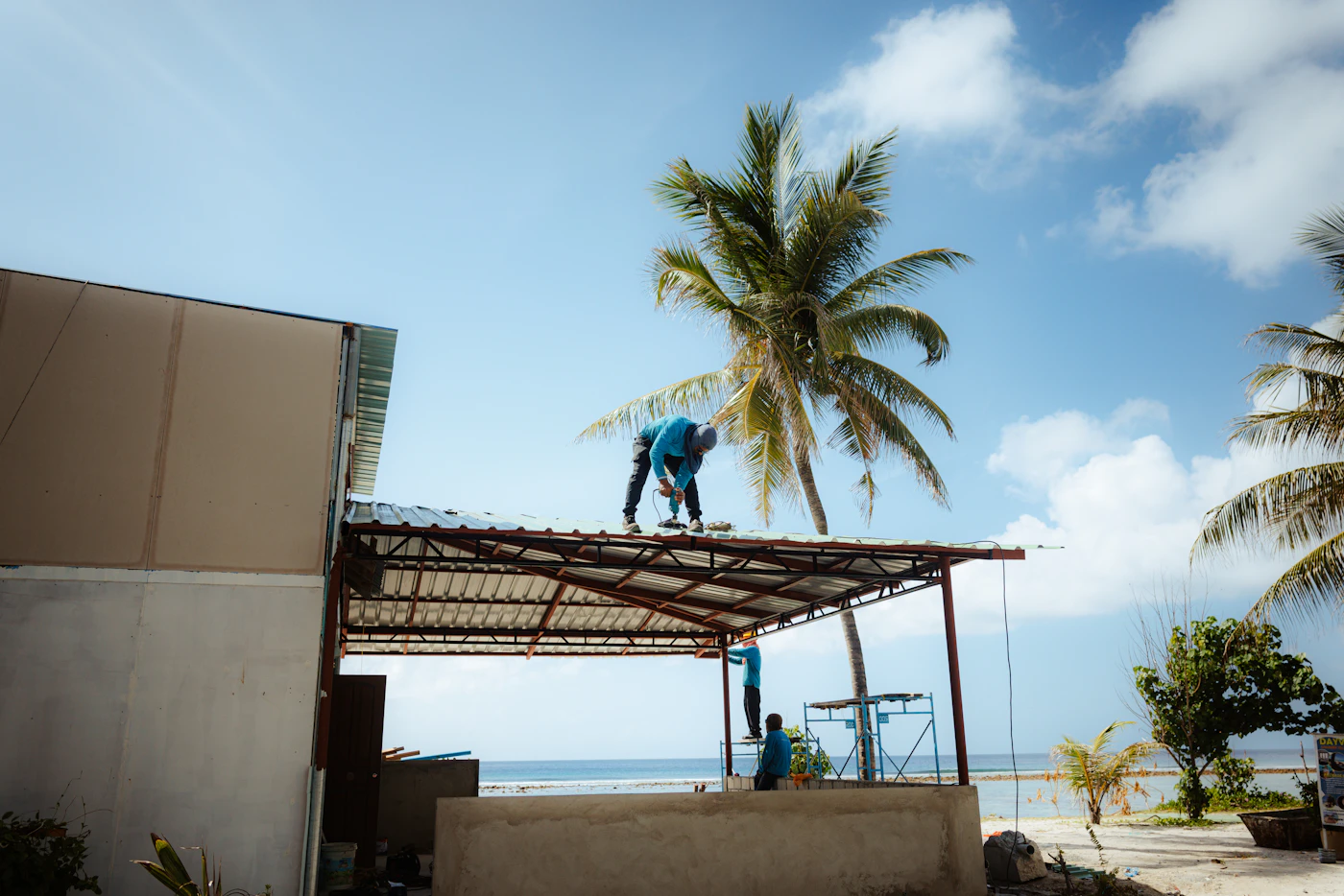 Contractors installing a metal roof on a beachside structure